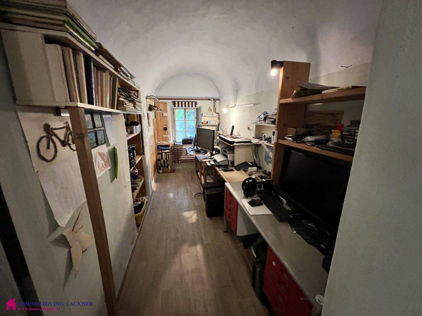 Langes Arbeitszimmer mit gewölbter Decke, Regalen und mehreren Arbeitsplätzen.