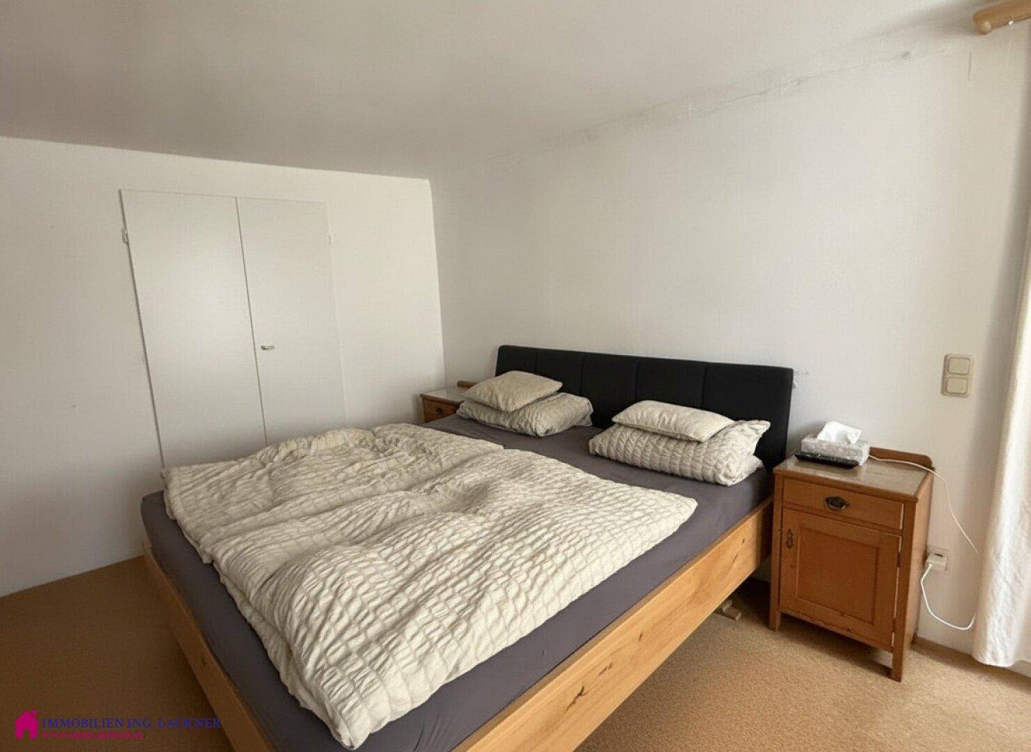 Schlafzimmer mit Doppelbett, Nachttischen und einem Einbauschrank an der Wand.