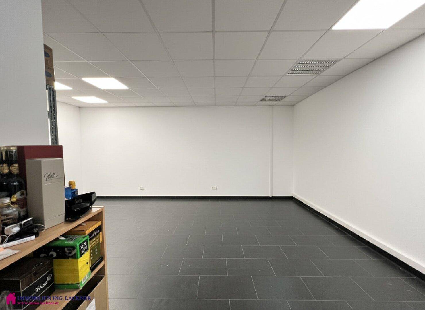 Großer, heller Bürobereich mit dunklem Fliesenboden und weiß gestrichenen Wänden, bereit zur Nutzung.