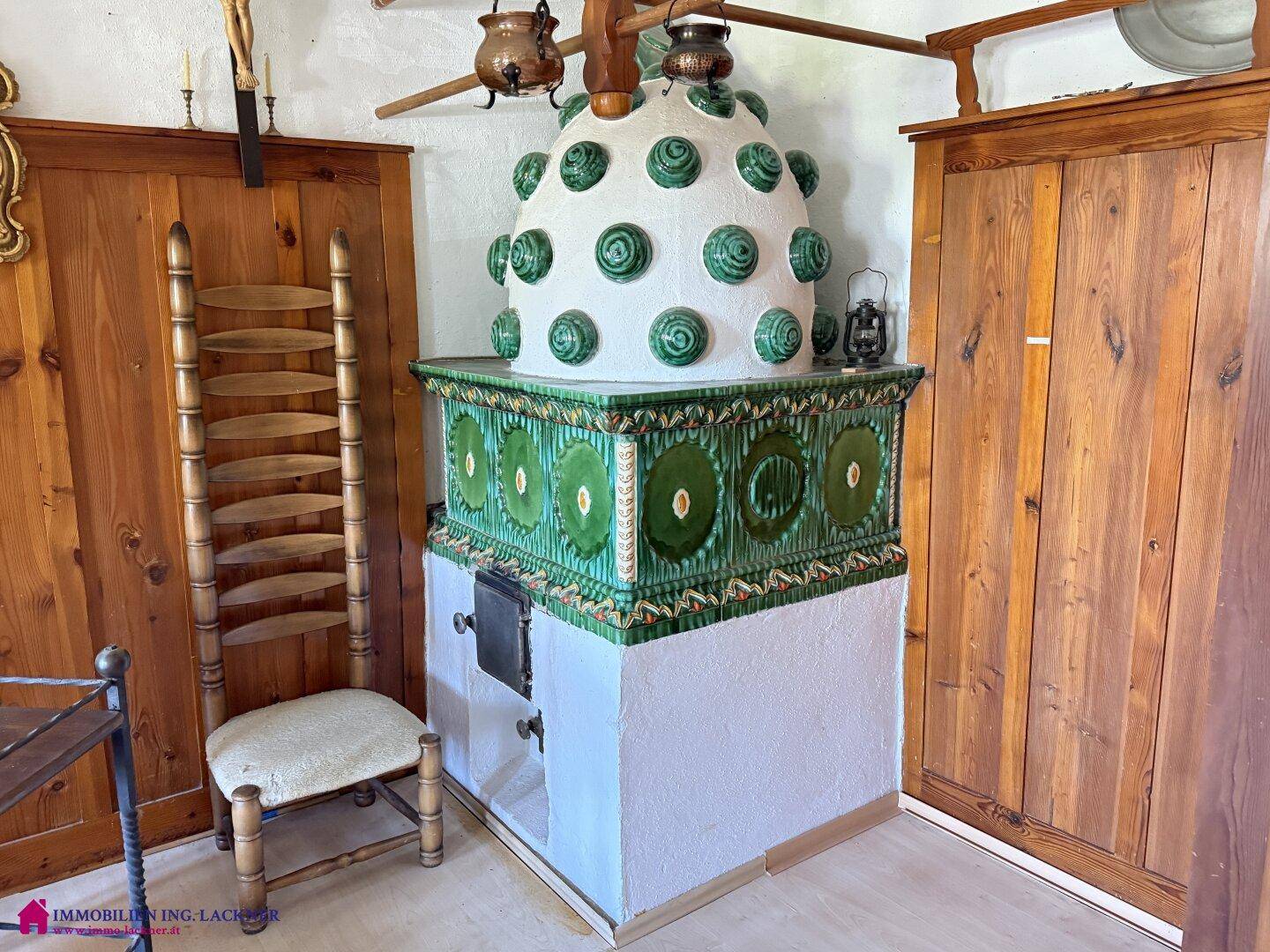 Traditioneller Kachelofen mit grünen Verzierungen in einem holzvertäfelten Raum.