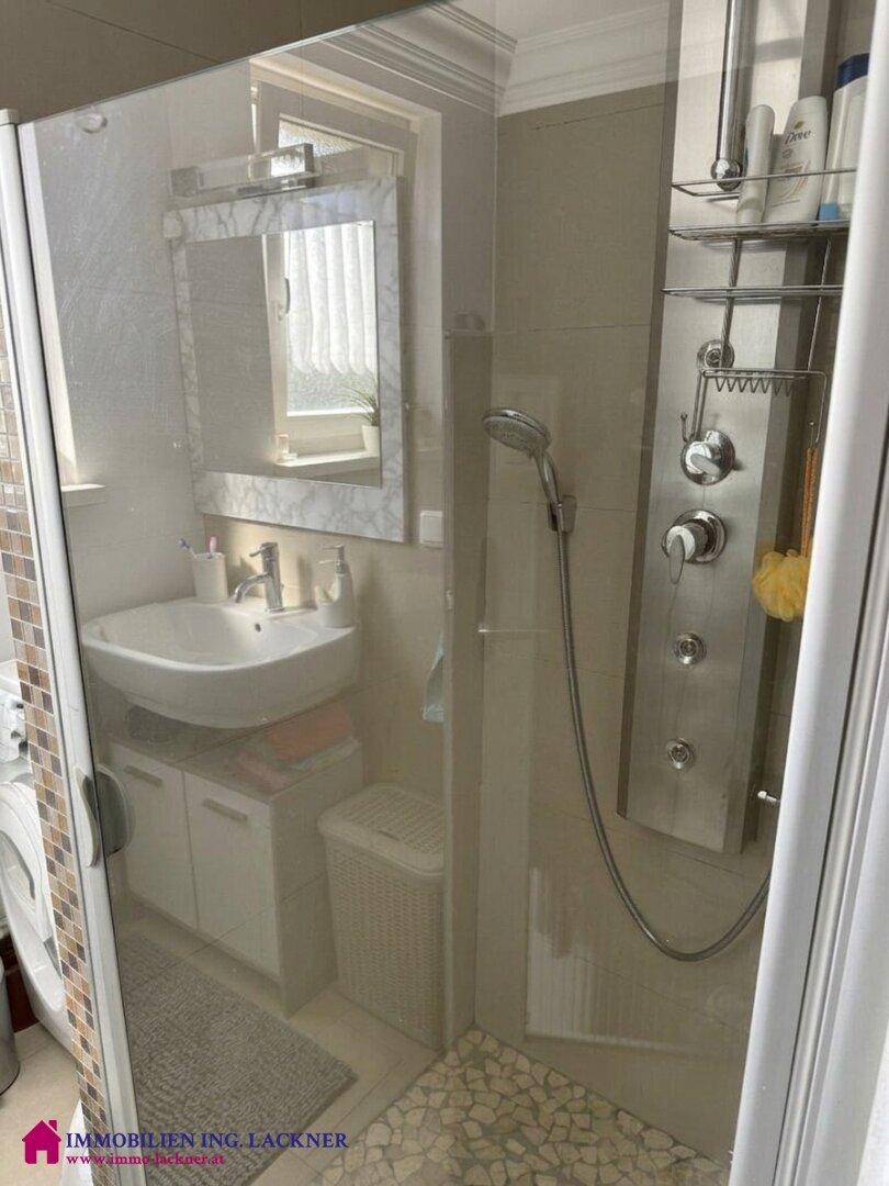 Duschkabine im Badezimmer mit moderner Duschsäule und Glasabtrennung.