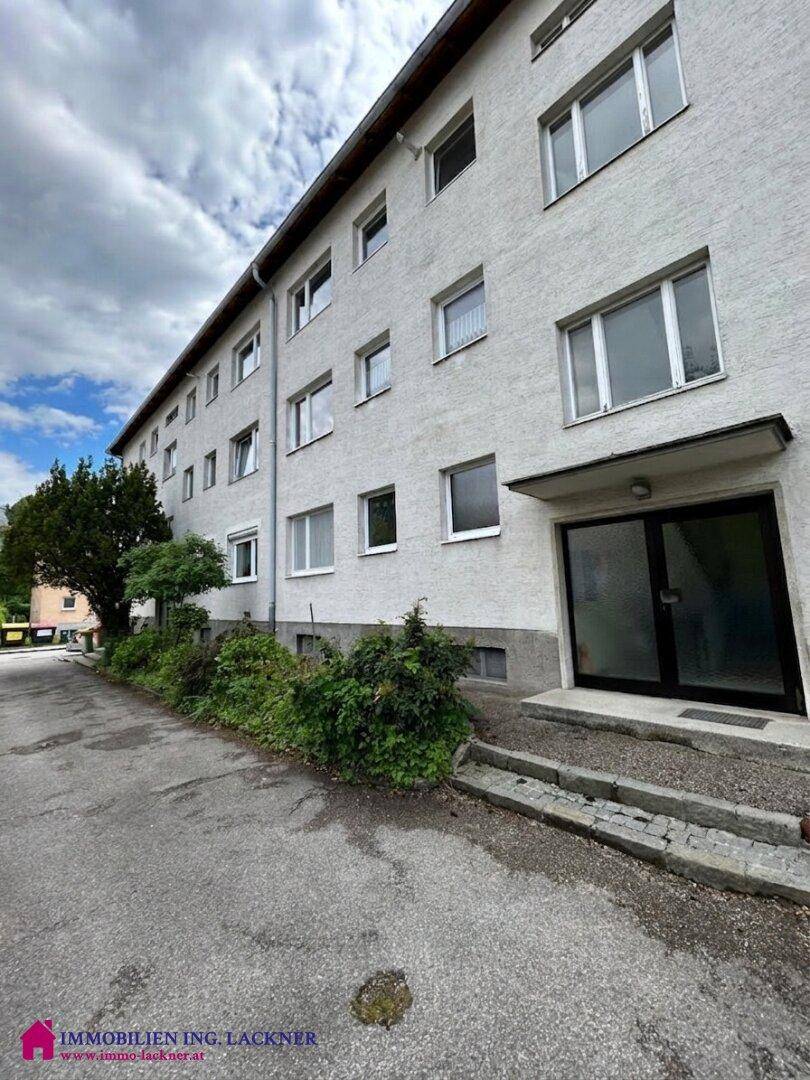 Fassade eines Mehrfamilienhauses mit mehreren Fenstern und einem einladenden Eingangsbereich.