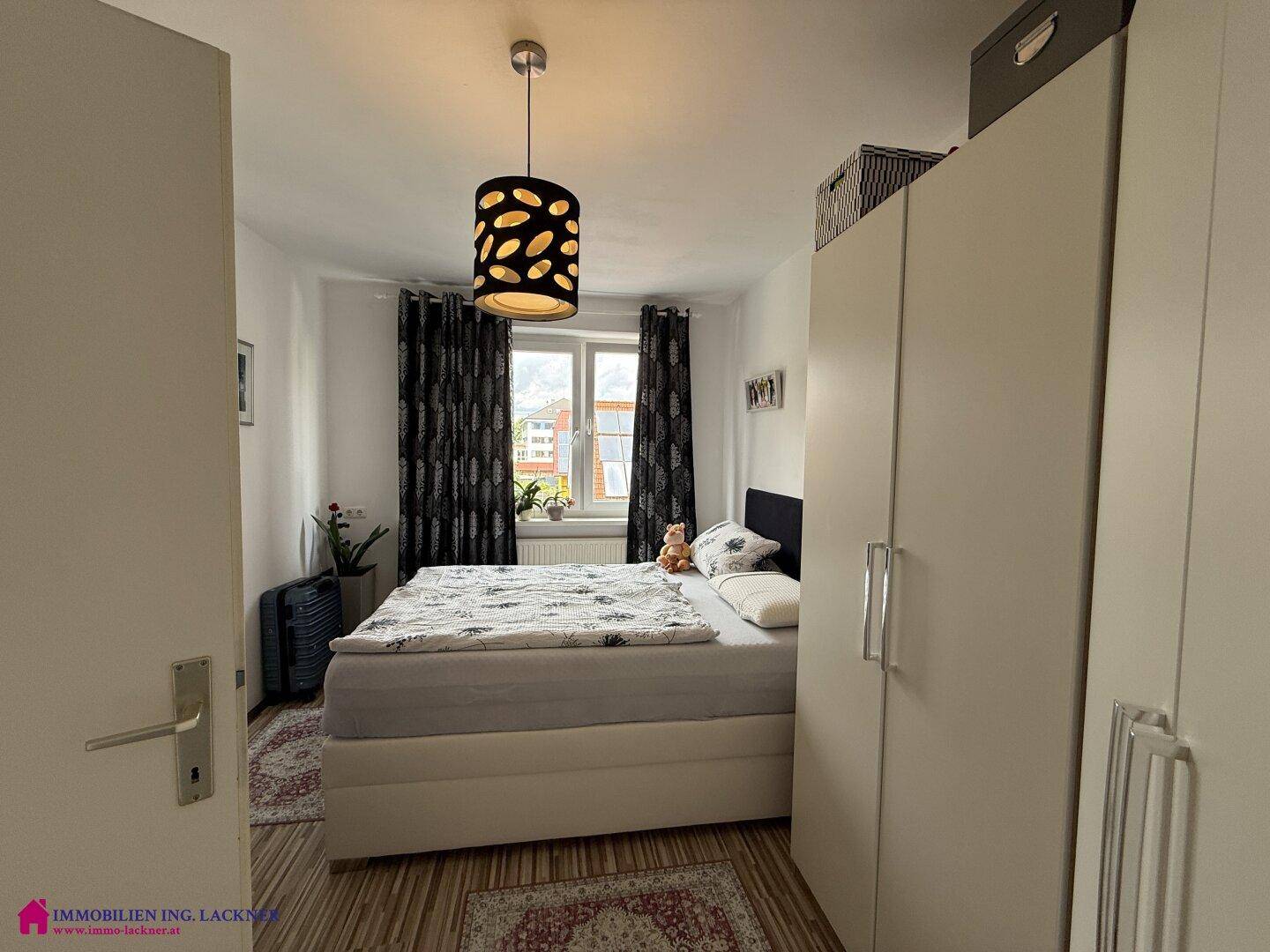 Schlafzimmer mit Doppelbett, Kleiderschrank und Fenster mit Blick auf die Umgebung.