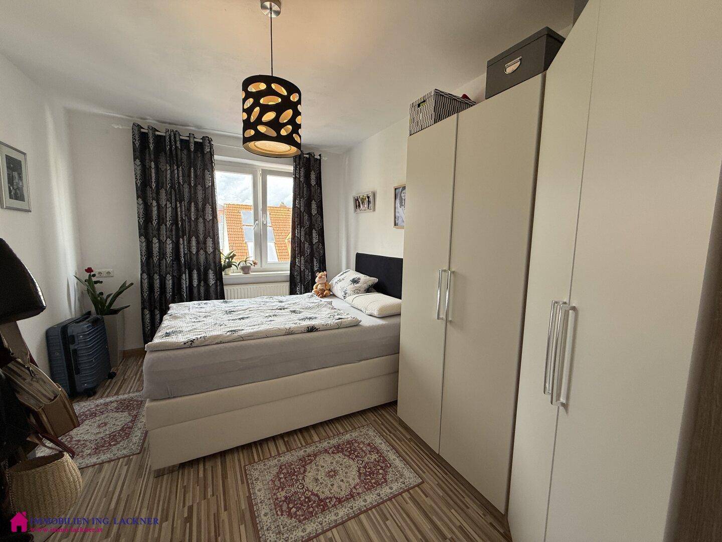 Geräumiges Schlafzimmer mit großem Bett, Kleiderschrank und Fenster für viel Tageslicht.