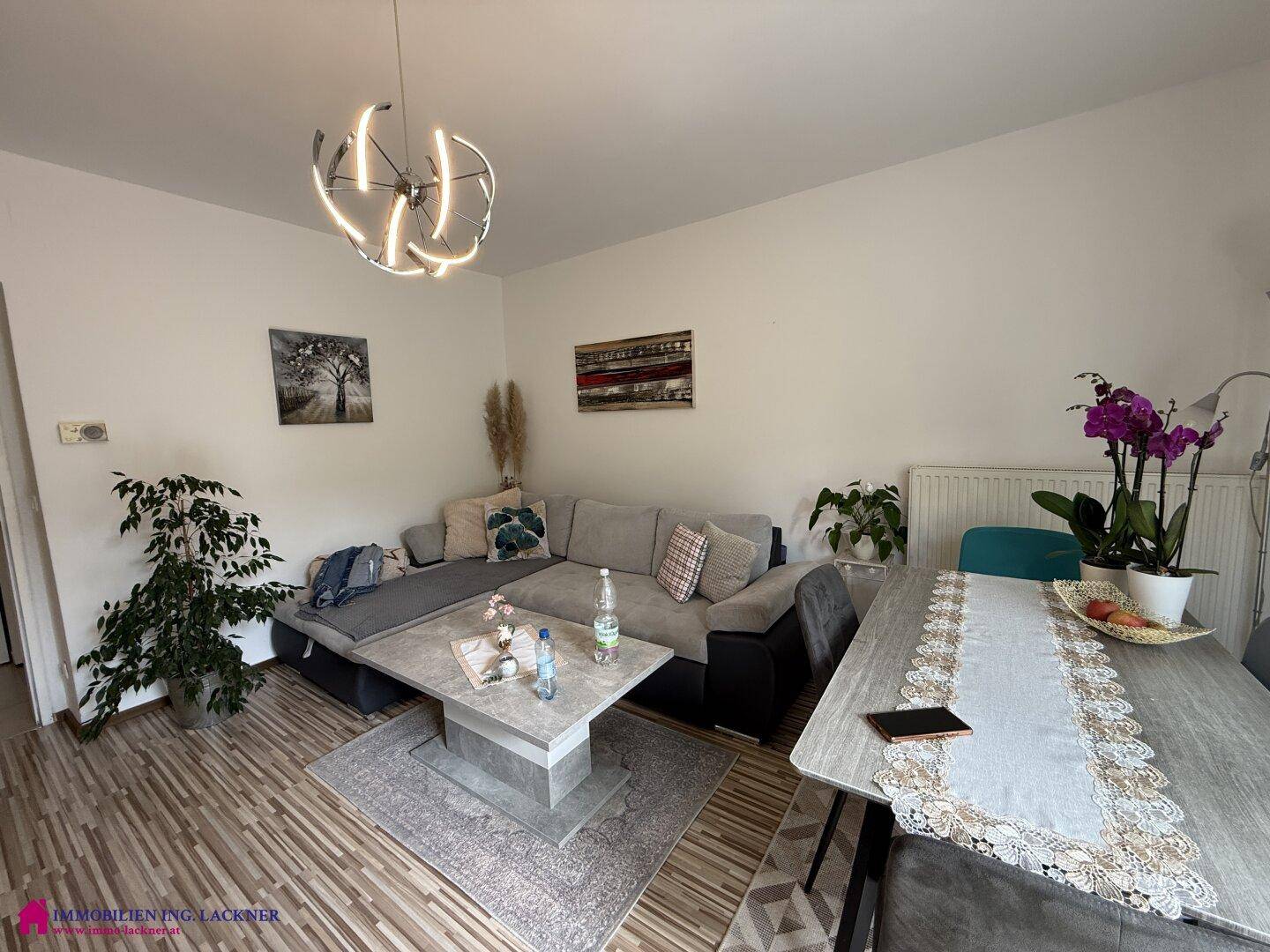 Heller Wohnbereich mit Ecksofa, Couchtisch und Essbereich, dekoriert mit Pflanzen.