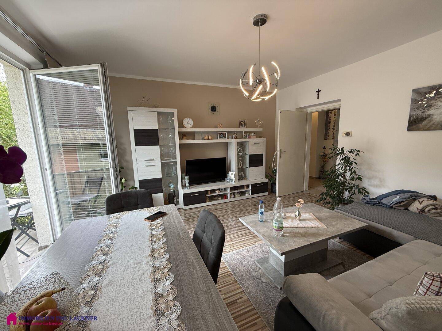 Gemütlicher Wohn- und Essbereich mit Sofa, Esstisch und Blick auf den Balkon.