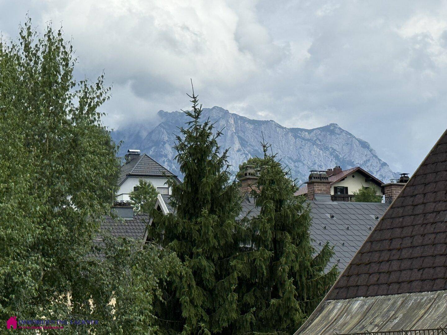 Panoramablick auf die umliegenden Berge und Dächer der Nachbarschaft unter bewölktem Himmel.