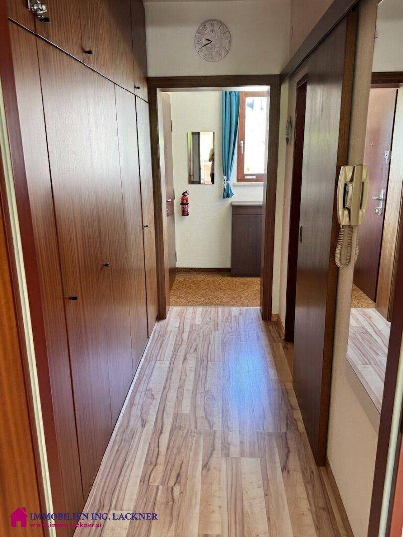 Langer Flur mit Holzschränken und Laminatboden, der zu weiteren Räumen führt.