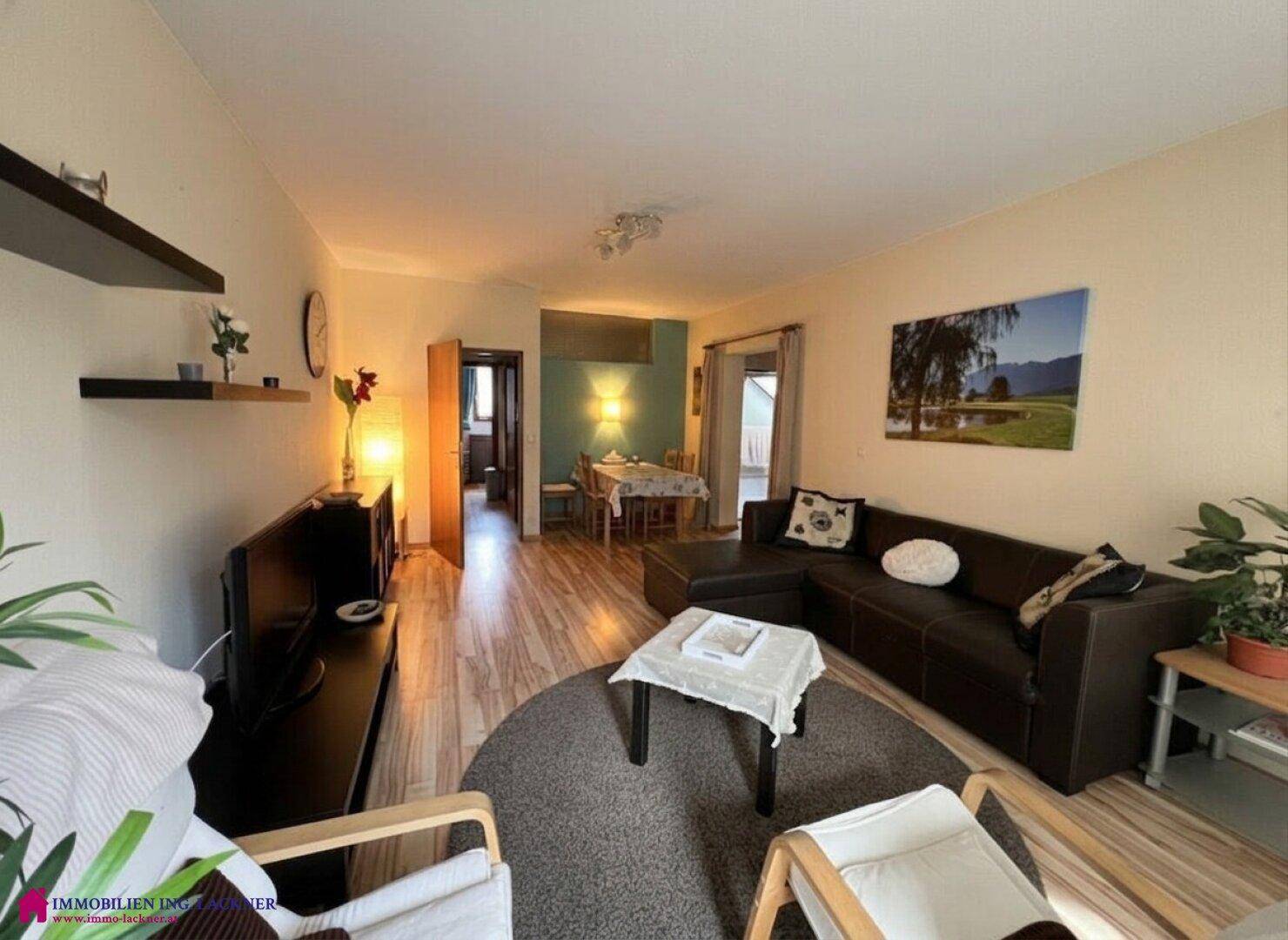 Geräumiger Wohn-Essbereich mit beigem Sofa, Laminatboden und Blick auf den Essbereich.