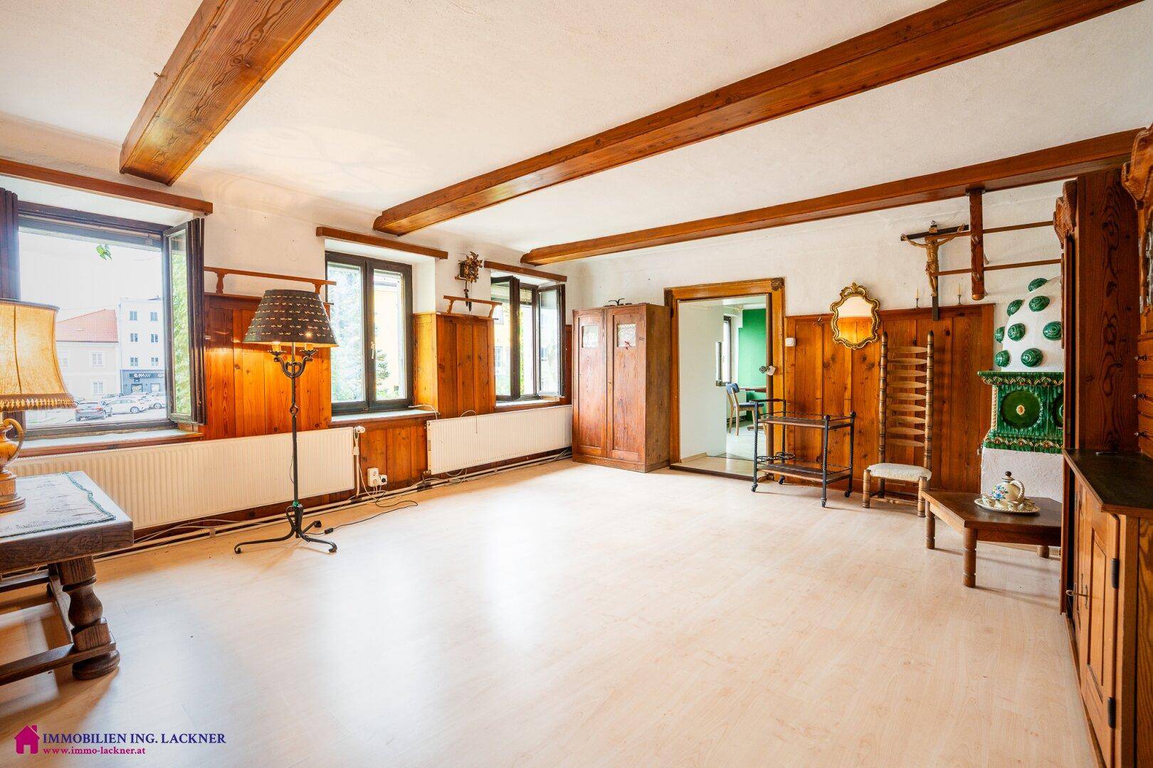 Geräumiges Wohnzimmer im alpinen Stil mit Holzbalken, Dielenboden und traditionellen Fenstern.