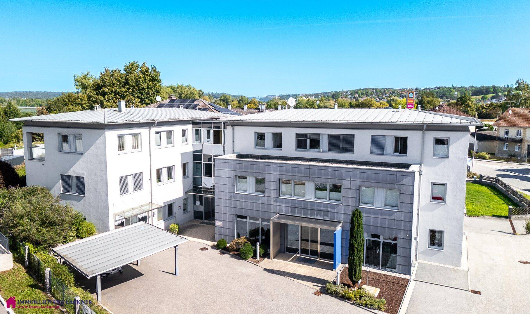 Gesamtansicht des modernen Bürokomplexes mit Carport und umliegender Landschaft bei Tageslicht.