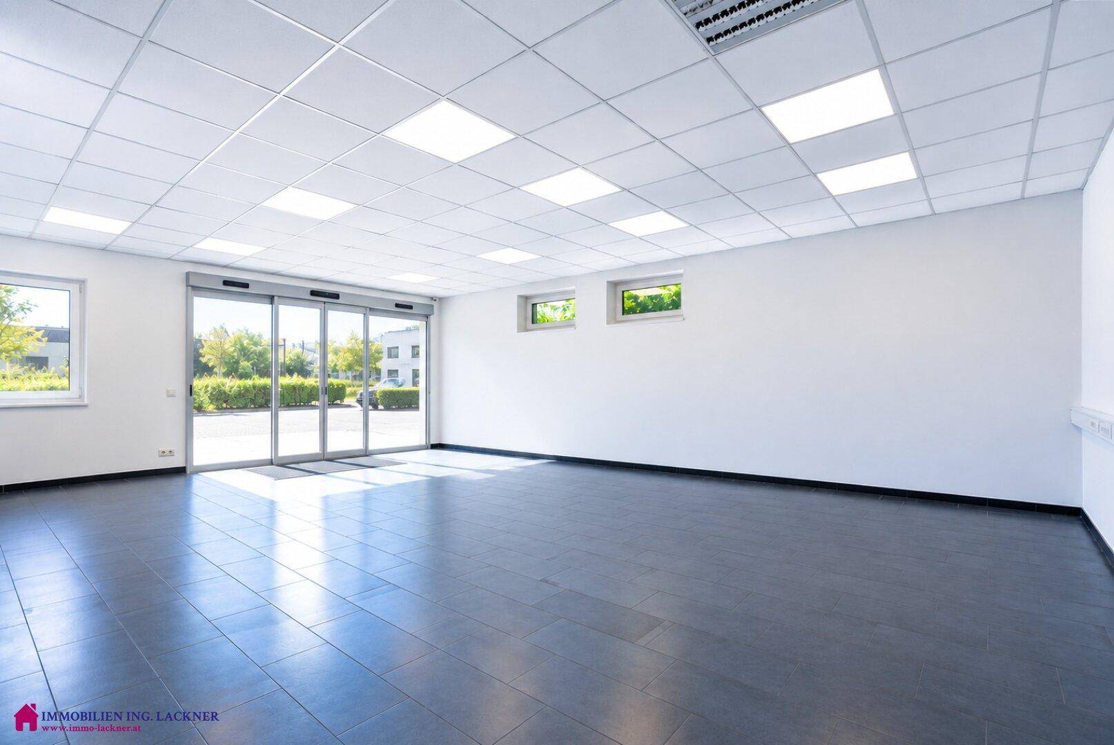 Offener Bürobereich mit viel Tageslicht durch große Fenster und Schiebetüren.