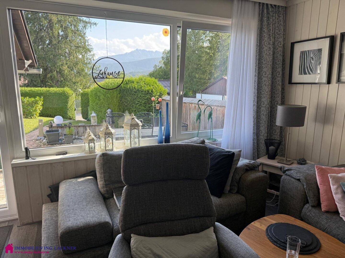 Lichtdurchfluteter Wohnbereich mit großen Fenstern, bequemen Sesseln und Bergblick.