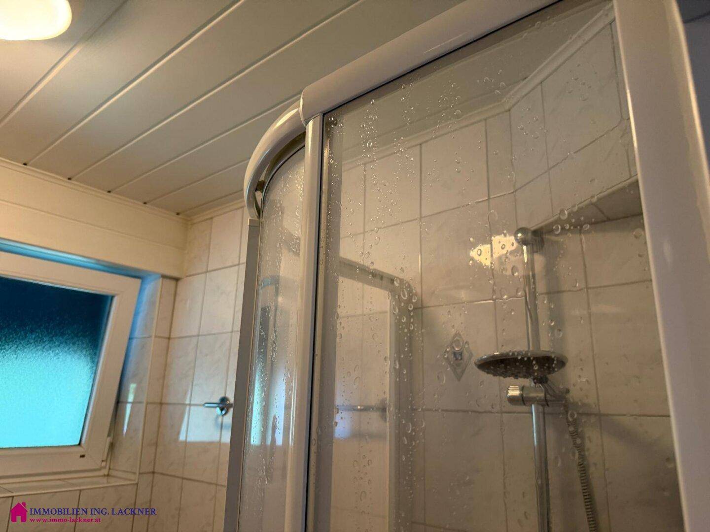 Duschbereich im Badezimmer mit Glasabtrennung und Duschkopf.