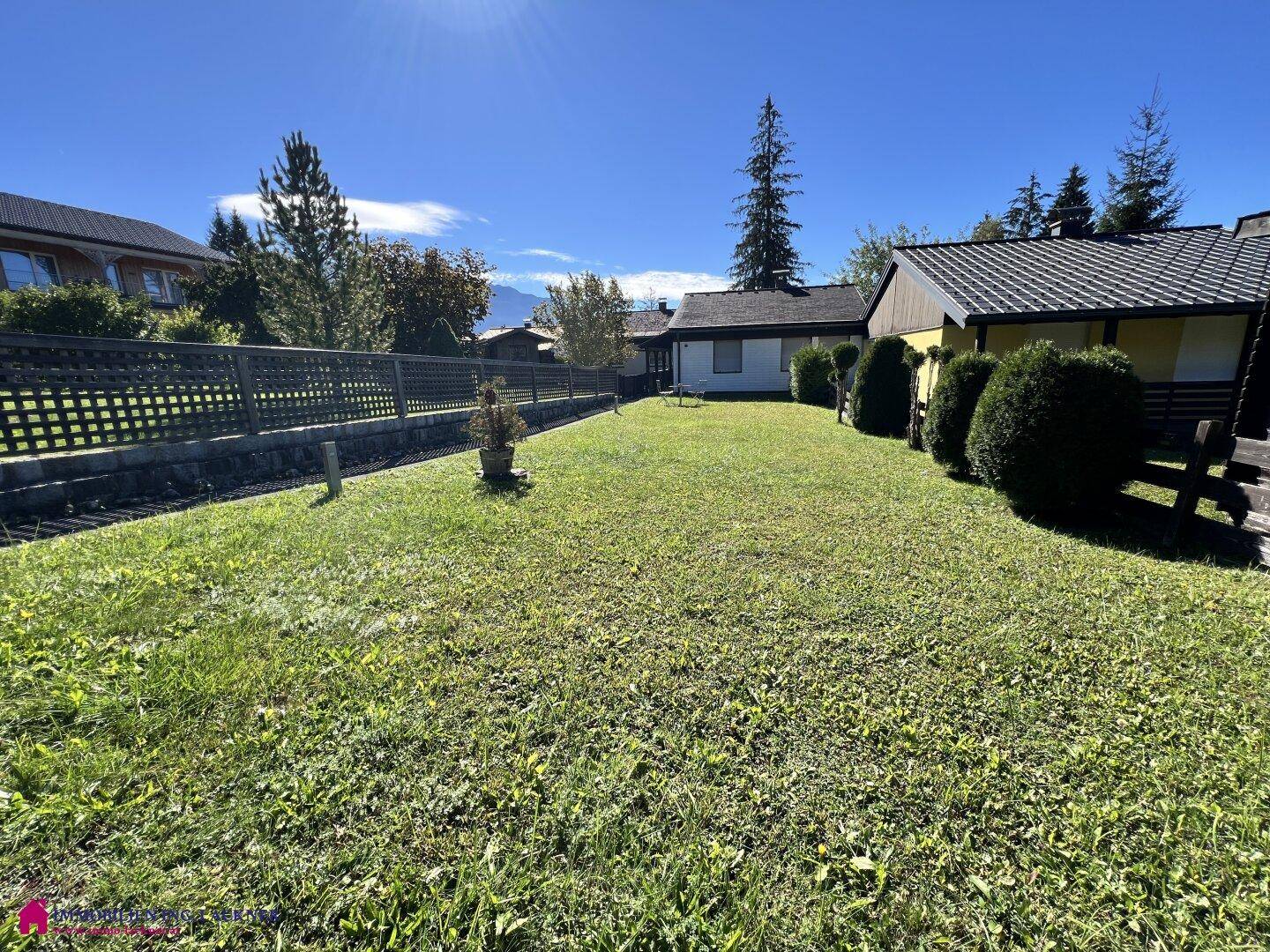 Weitläufige Rasenfläche im Garten mit Blick auf die umliegende Natur und Berge.