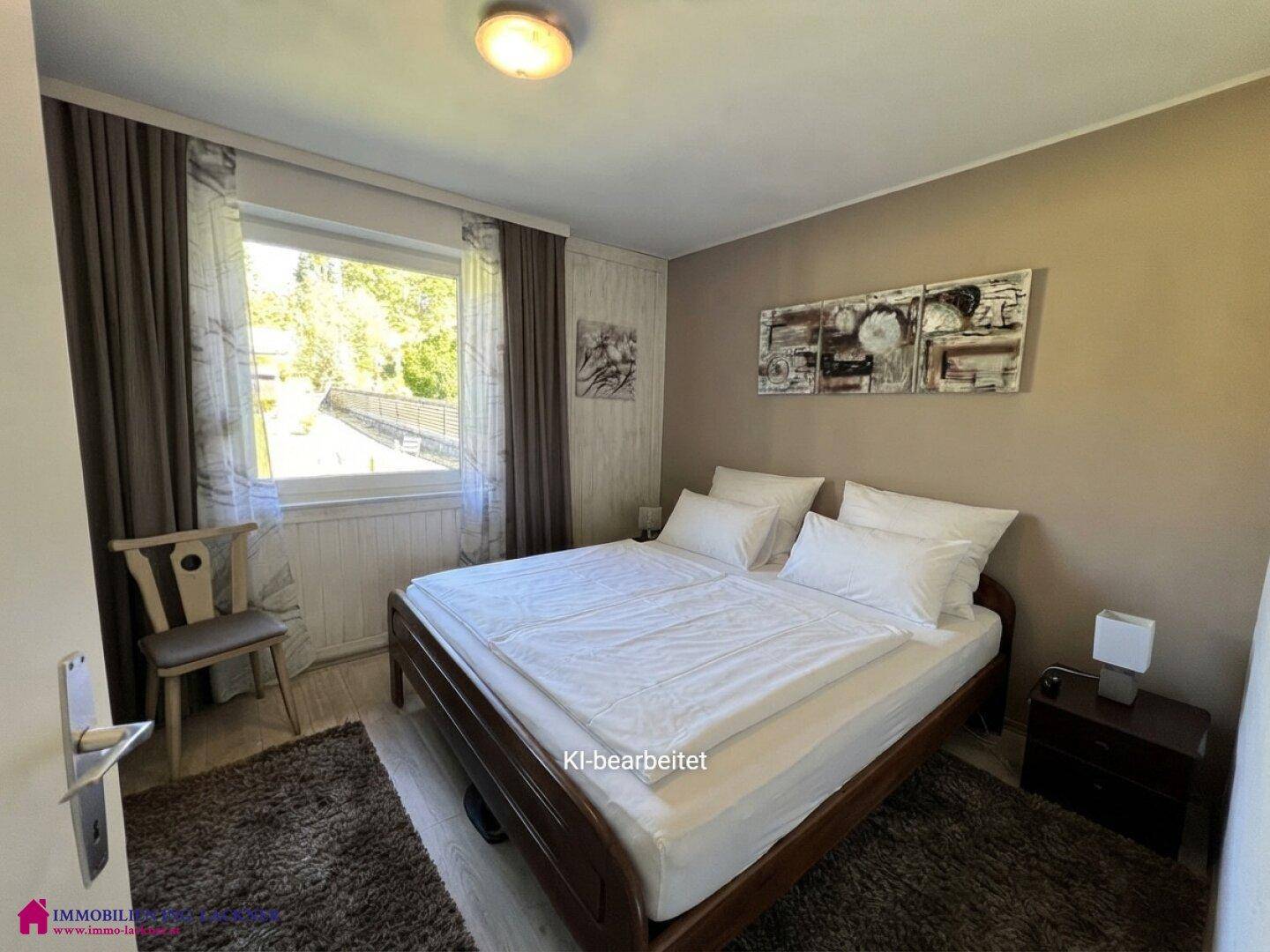 Gemütliches Schlafzimmer mit Doppelbett, hellem Boden und Blick ins Grüne durch das Fenster.