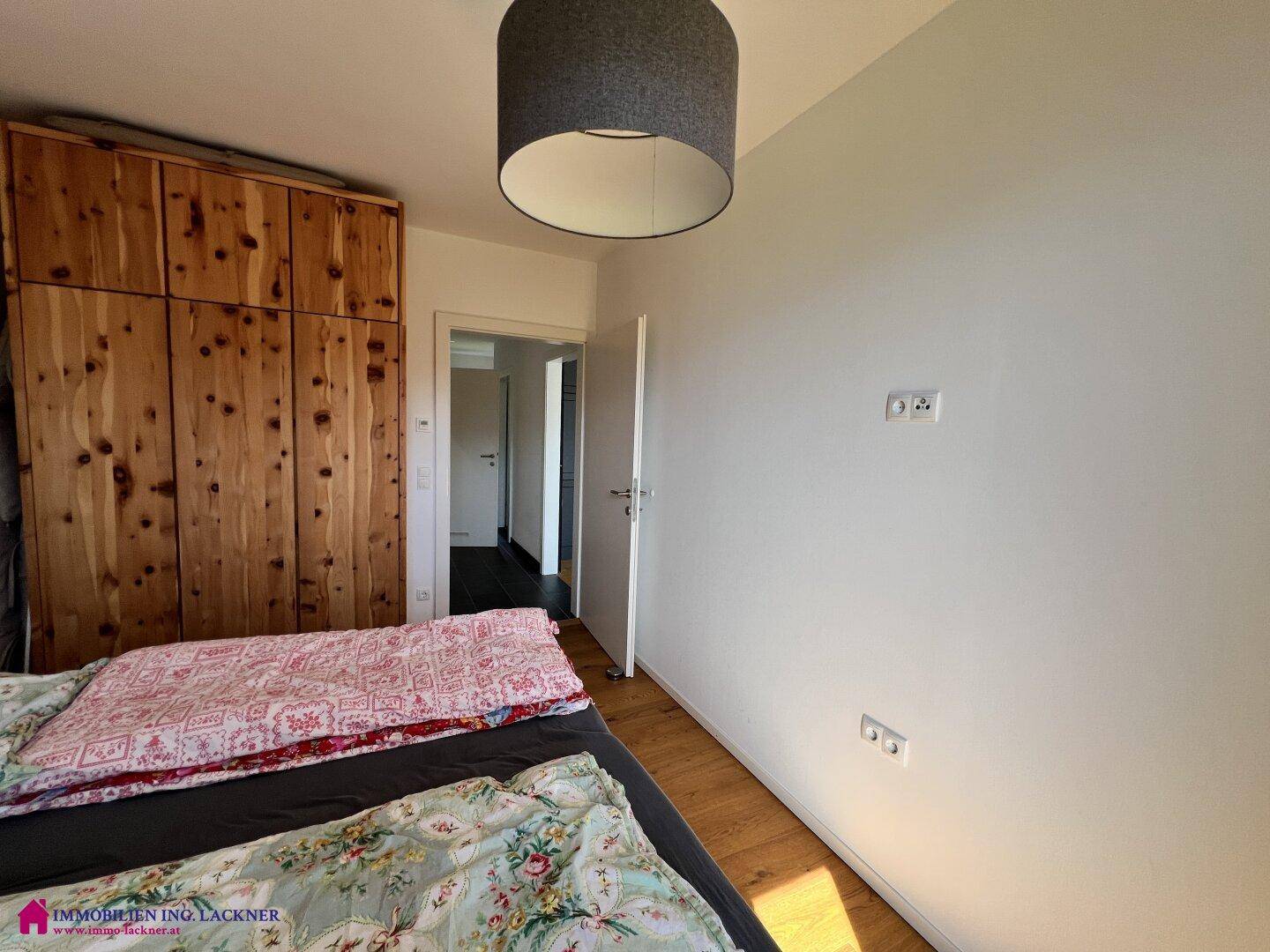 Schlafzimmer mit Holzbett, großem Holzschrank und Zugang zum Flur.