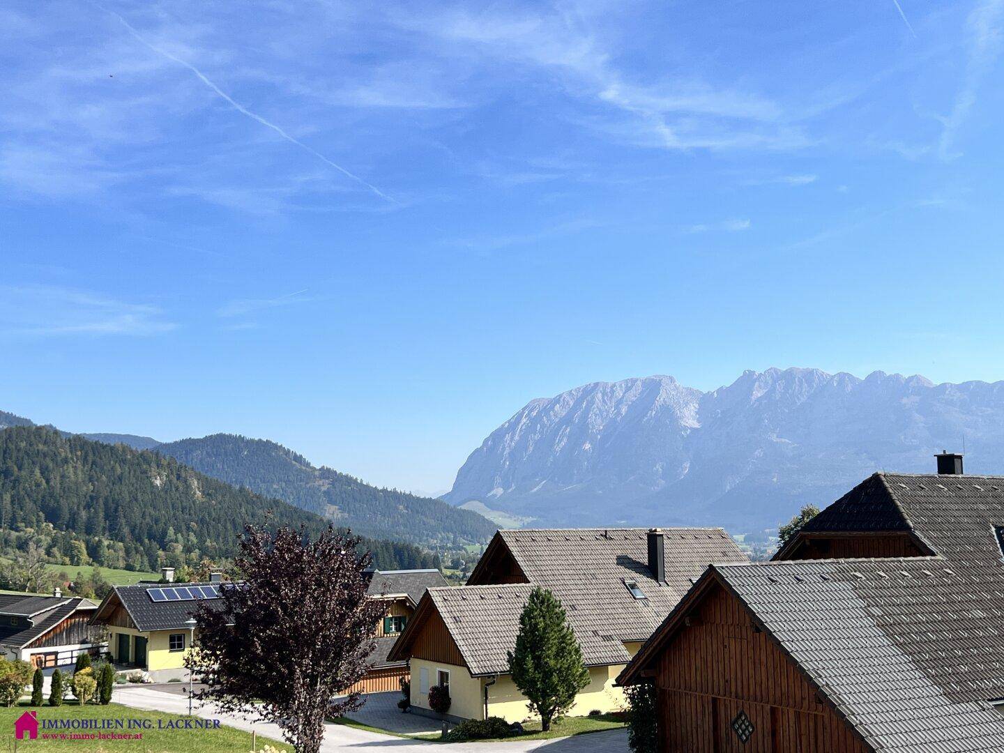Weitläufiger Blick über eine Siedlung mit traditionellen Häusern und einer beeindruckenden Bergkulisse.