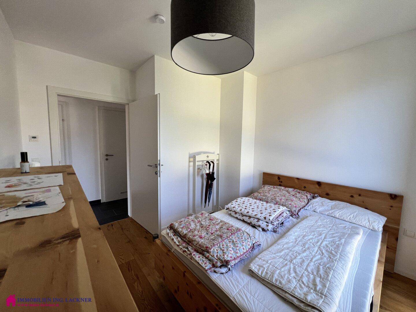 Helles Schlafzimmer mit Holzbett, Holzboden und schlichtem, funktionalem Design.