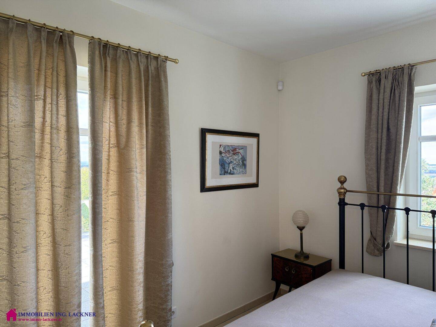 Gemütliches Schlafzimmer mit Fenster, Nachttisch und klassischem Metallbettgestell.