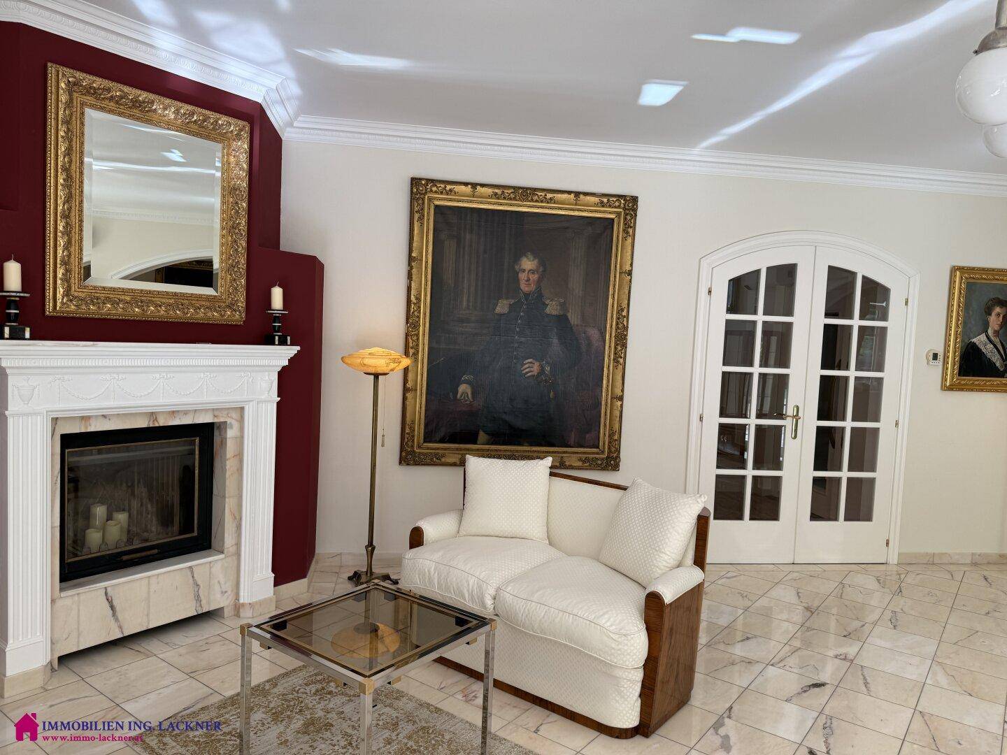 Klassisch eingerichtetes Wohnzimmer mit Kamin, eleganten Möbeln und großformatigen Gemälden.