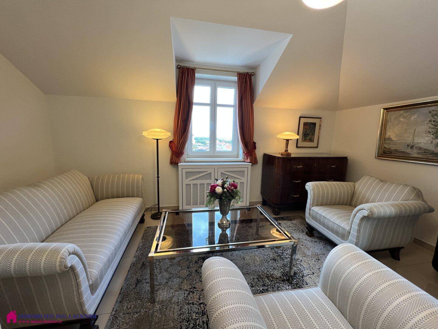 Stilvolles Wohnzimmer mit gestreiften Sofas, Couchtisch und Dachschrägenfenster.