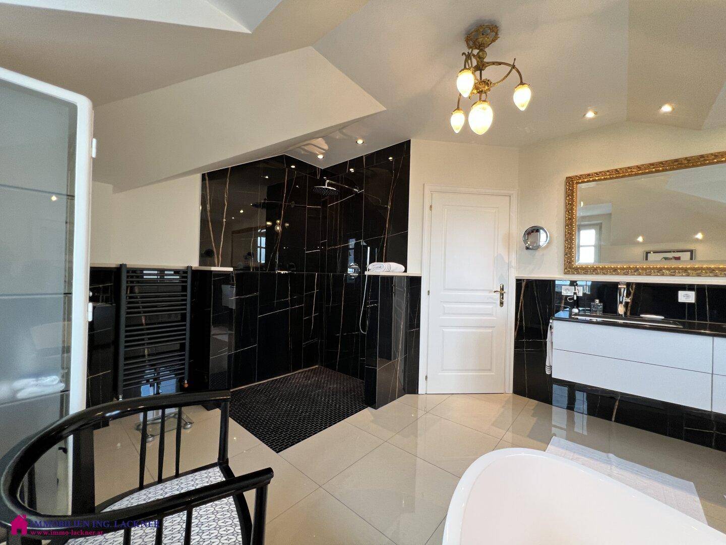 Elegantes Badezimmer mit großer begehbarer Dusche, schwarzen Fliesen und Heizkörper.