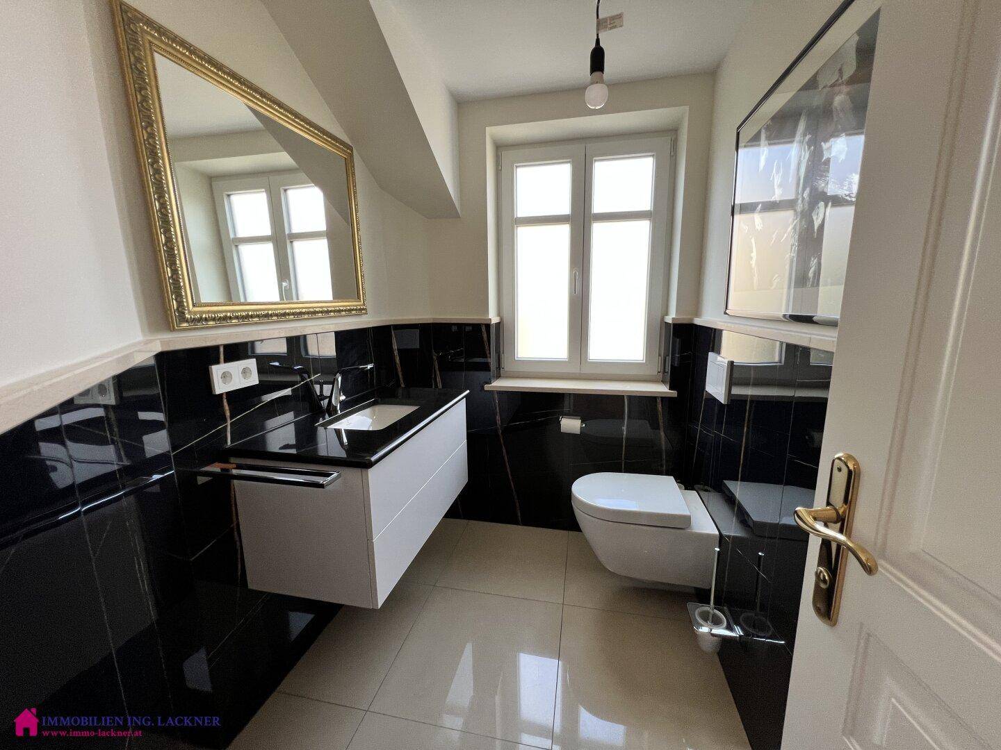 Modernes Badezimmer mit wandhängendem WC, Einzelwaschbecken und Fenster.