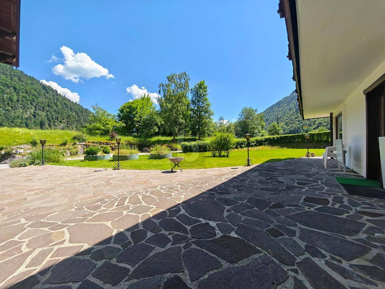 Große gepflasterte Terrasse mit Blick auf die Berge und die umliegende grüne Landschaft.