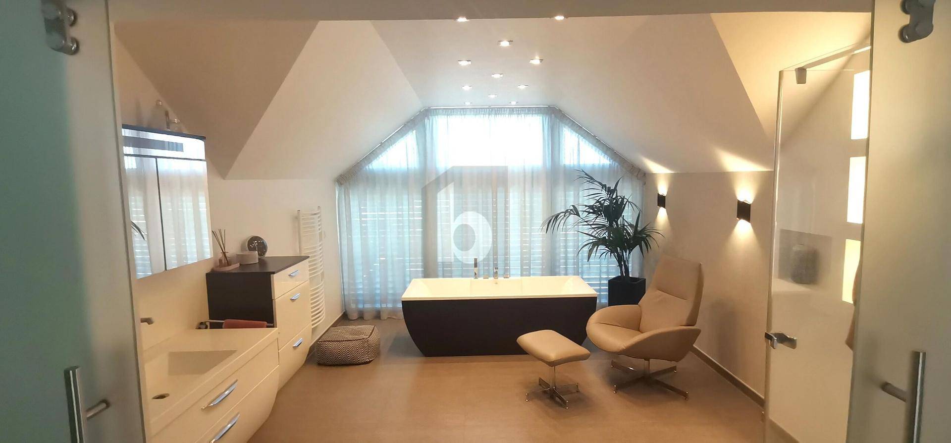 Geräumiges Dachgeschossbad mit freistehender Badewanne, großem Fenster und viel Tageslicht.