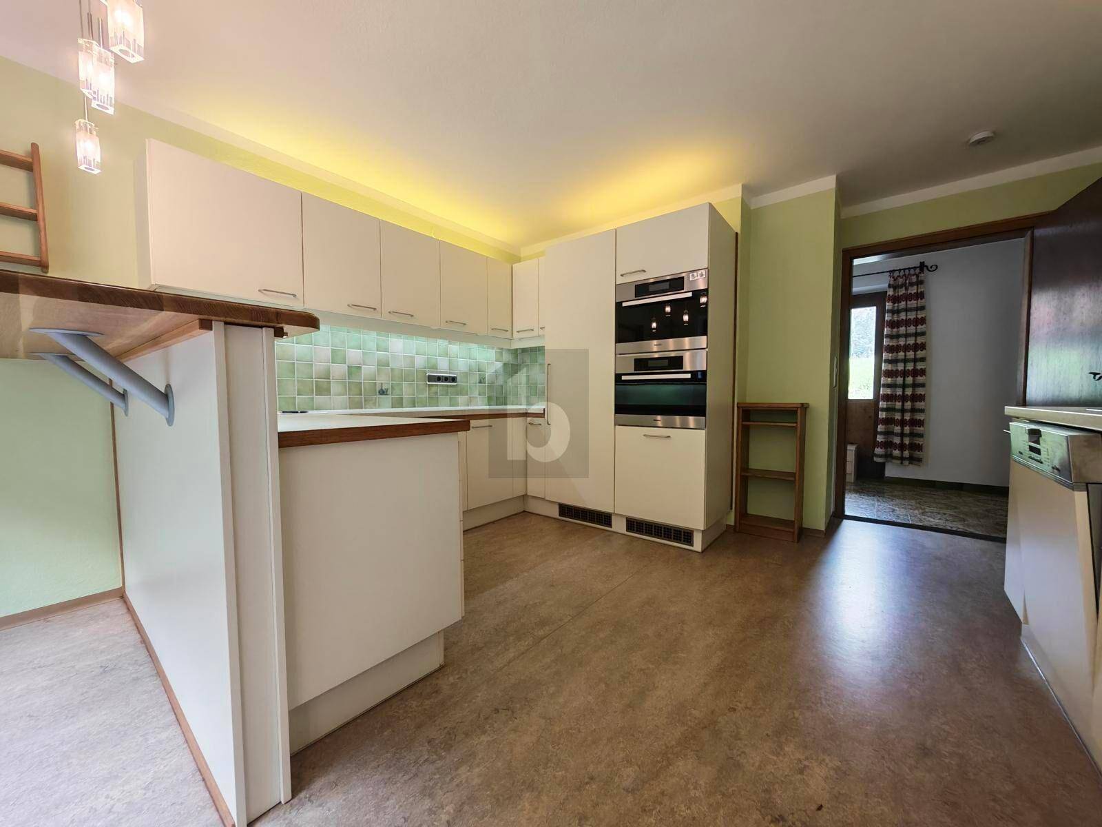 Helle, semi-offene Küche mit weißen Einbauschränken, integrierten Doppelöfen und modernem Design.