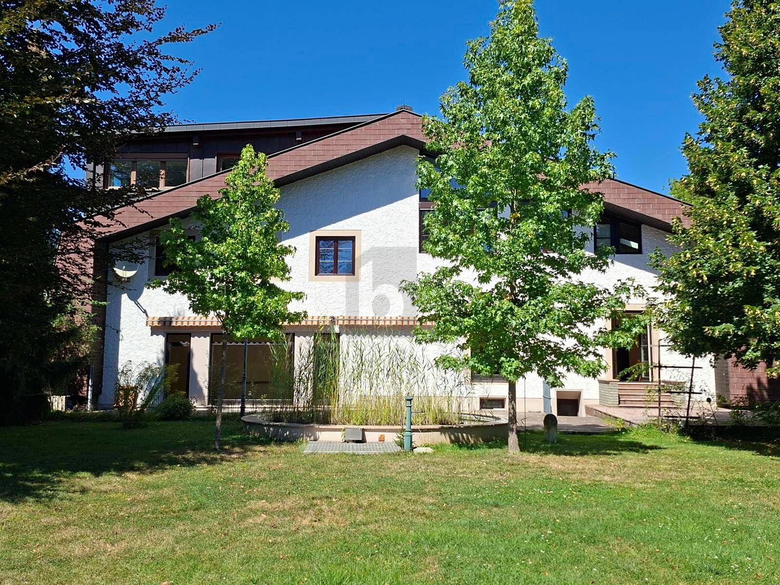 Ansicht des Hauses mit weißer Fassade, braunem Dach und gepflegtem Gartenbereich.