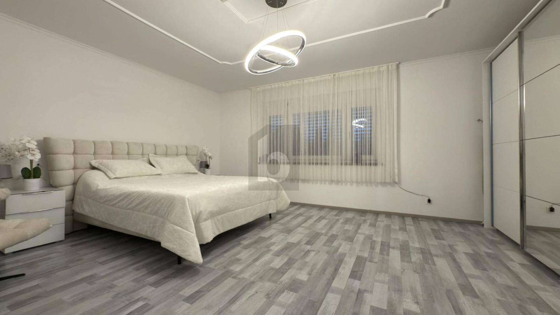 Helles Schlafzimmer mit großem Bett, Spiegelschrank und modernem Laminatboden.