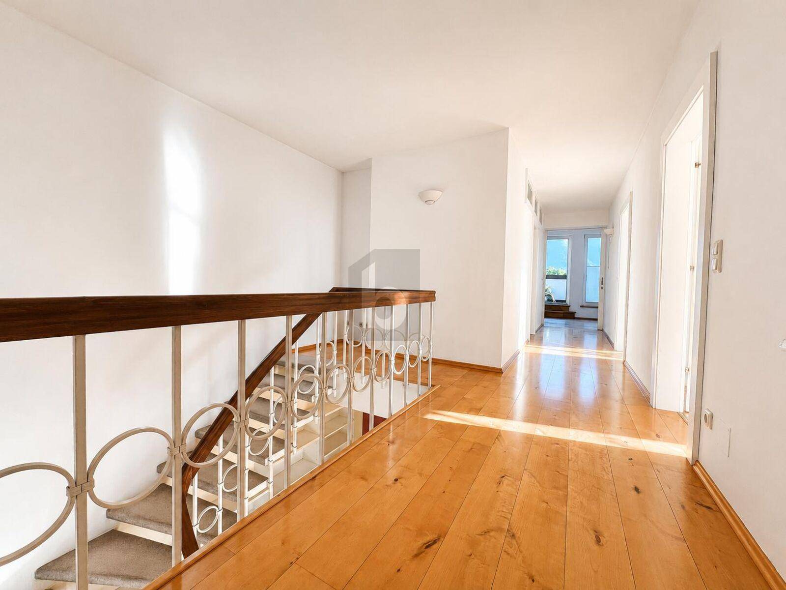 Heller Flur mit Holzfußboden und einer eleganten Treppe, die zu den oberen Etagen führt.
