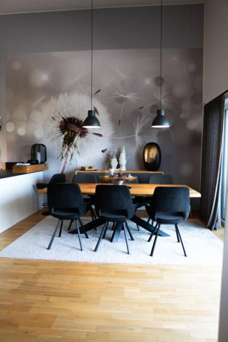 Eleganter Essbereich mit Holztisch, schwarzen Stühlen und dekorativer Wandgestaltung.