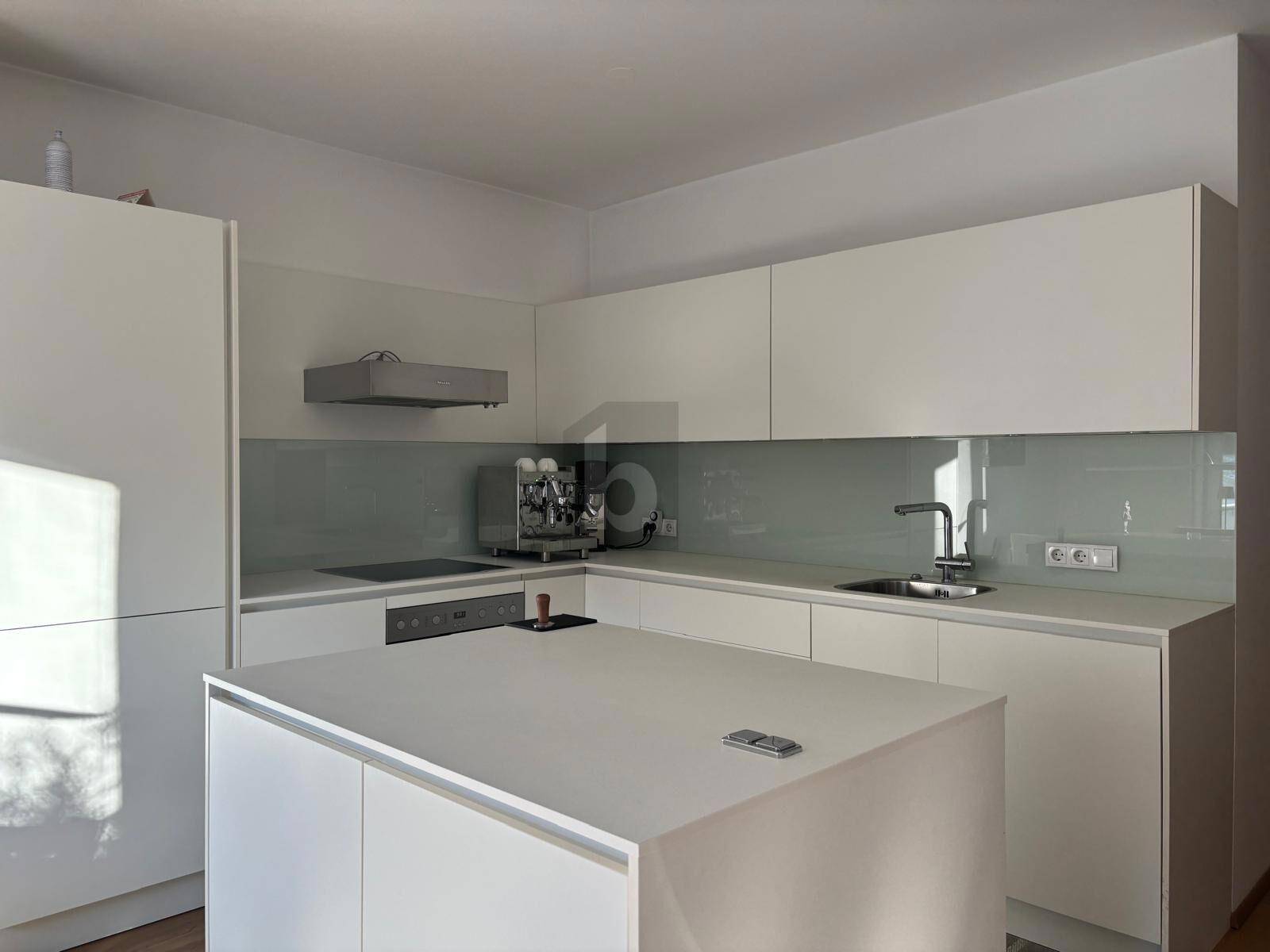 Moderne weiße Einbauküche mit Kochinsel, integrierten Geräten und minimalistischem Design.