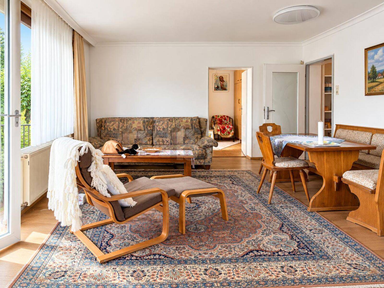 Heller Wohn- und Essbereich mit Zugang zum Balkon und traditioneller Einrichtung.