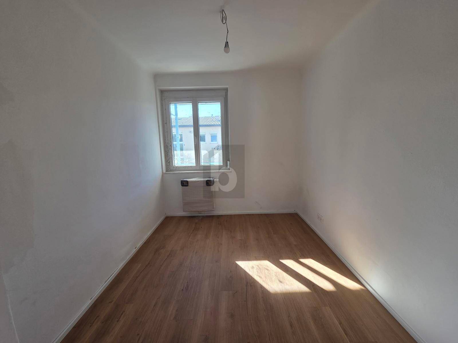Gemütliches Schlafzimmer mit neuem Laminatboden und einem Fenster, das viel Tageslicht hereinlässt.