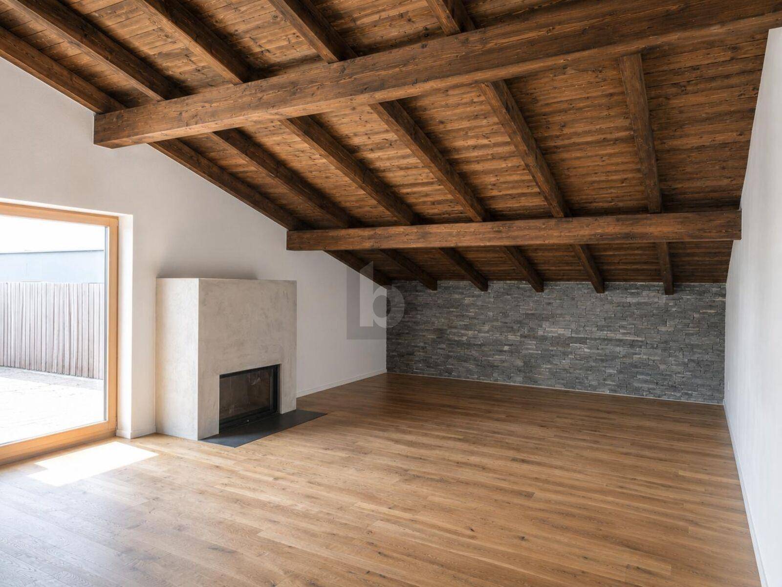 Geräumiger Wohnbereich mit Kamin, Holzbalkendecke und Akzentwand aus Stein.