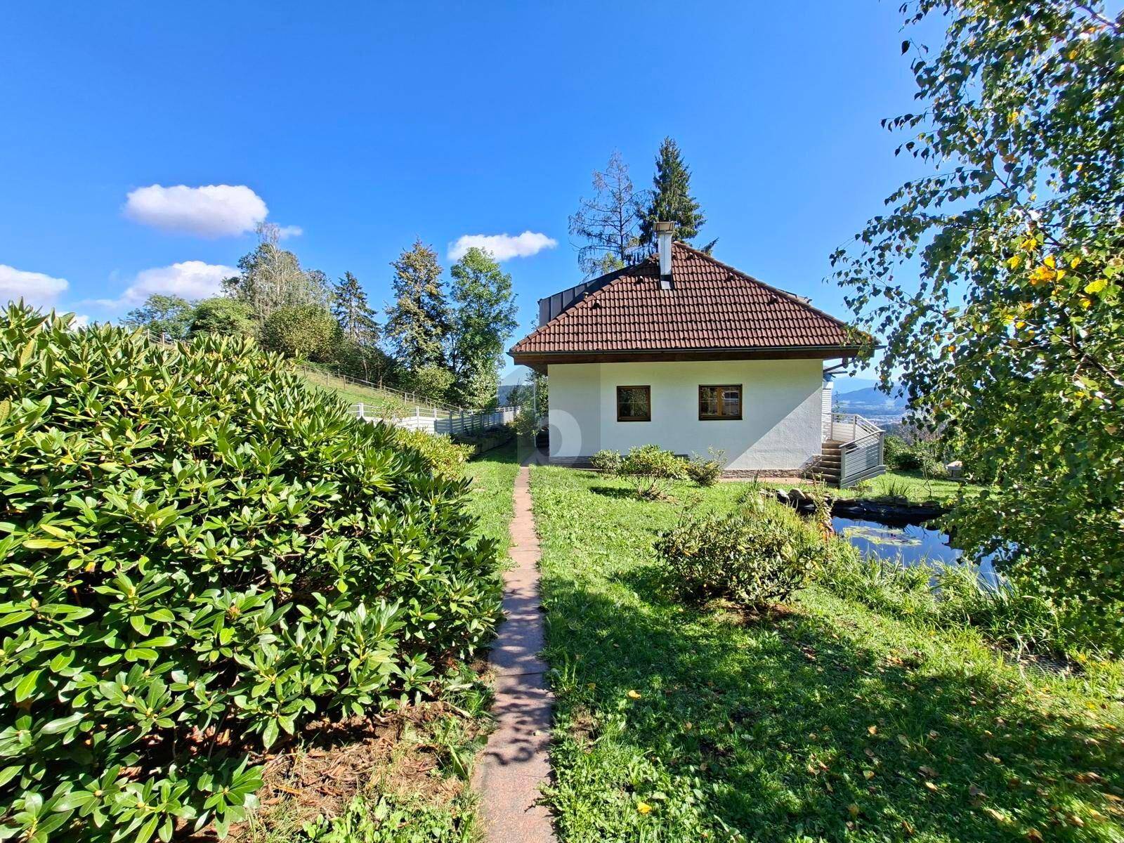 Charmantes Einfamilienhaus mit Satteldach, umgeben von einem gepflegten Garten und Hecken.