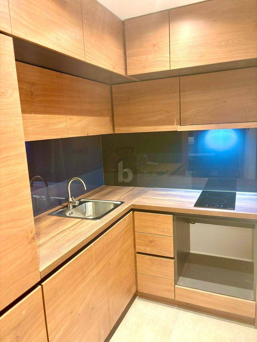 Moderne Holzküche mit Einbauschränken, Spüle, Induktionskochfeld und Arbeitsplatte aus Holz.