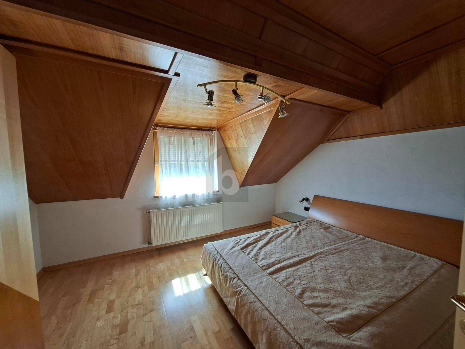 Gemütliches Schlafzimmer mit Holztäfelung, Dachschrägen und einem Doppelbett.