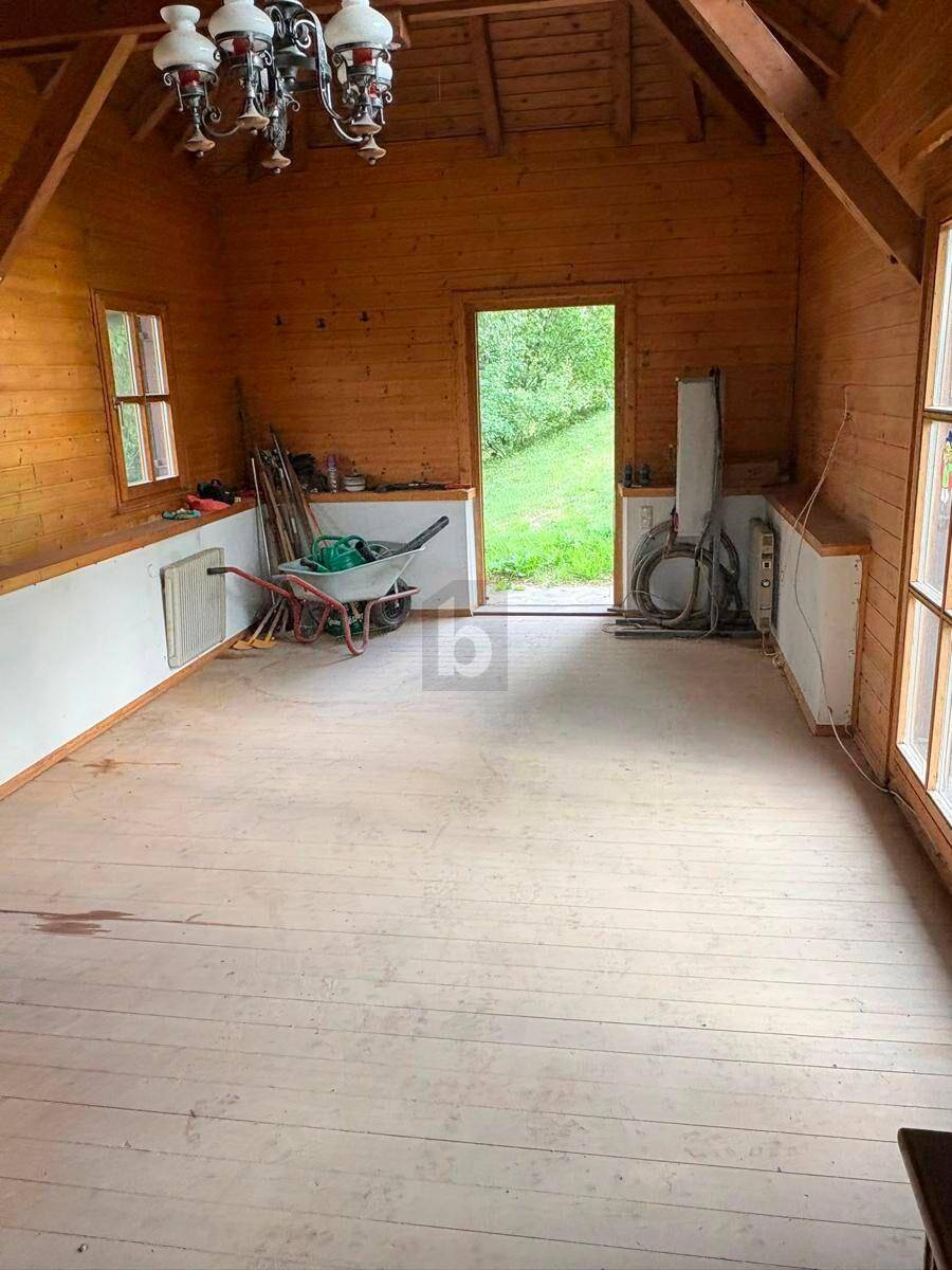 Heller Wohnraum mit Holzböden, freiliegenden Dachbalken und Zugang zum Gartenbereich.