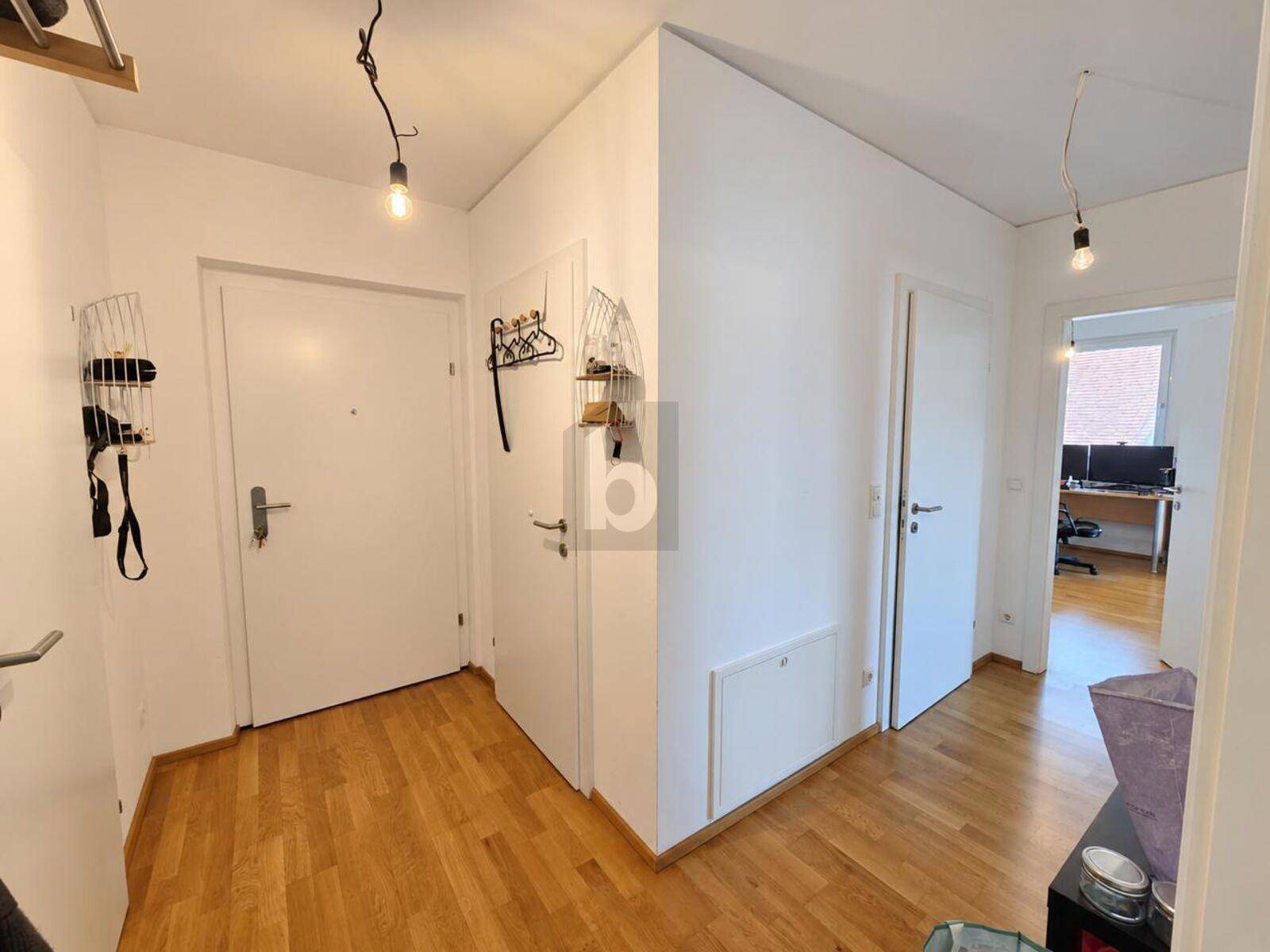 Heller Flur mit Holzboden und Zugang zu verschiedenen Räumen der Wohnung.