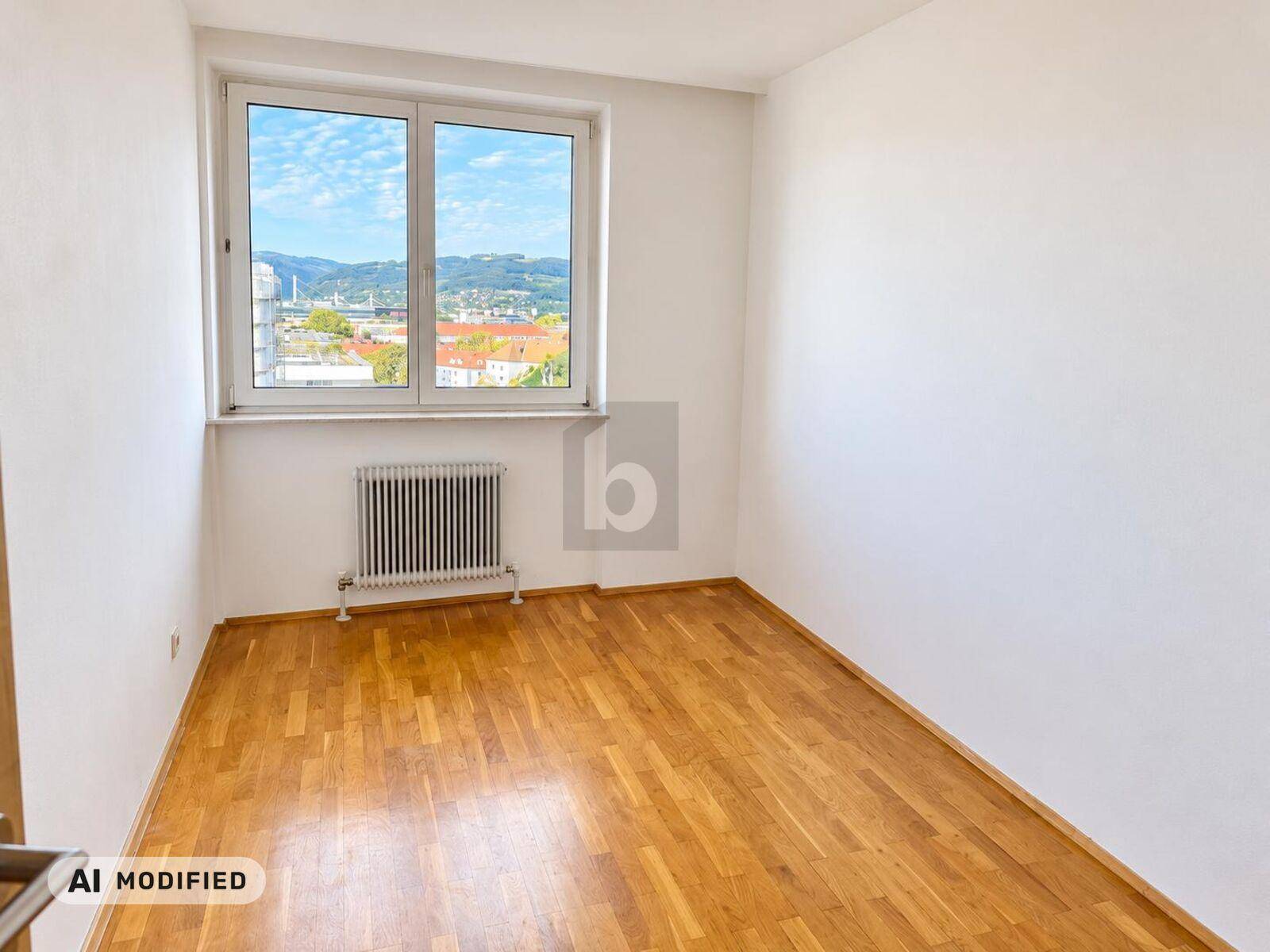 Helles Zimmer mit Holzparkett und Fenster, das einen weiten Blick auf die Umgebung ermöglicht.