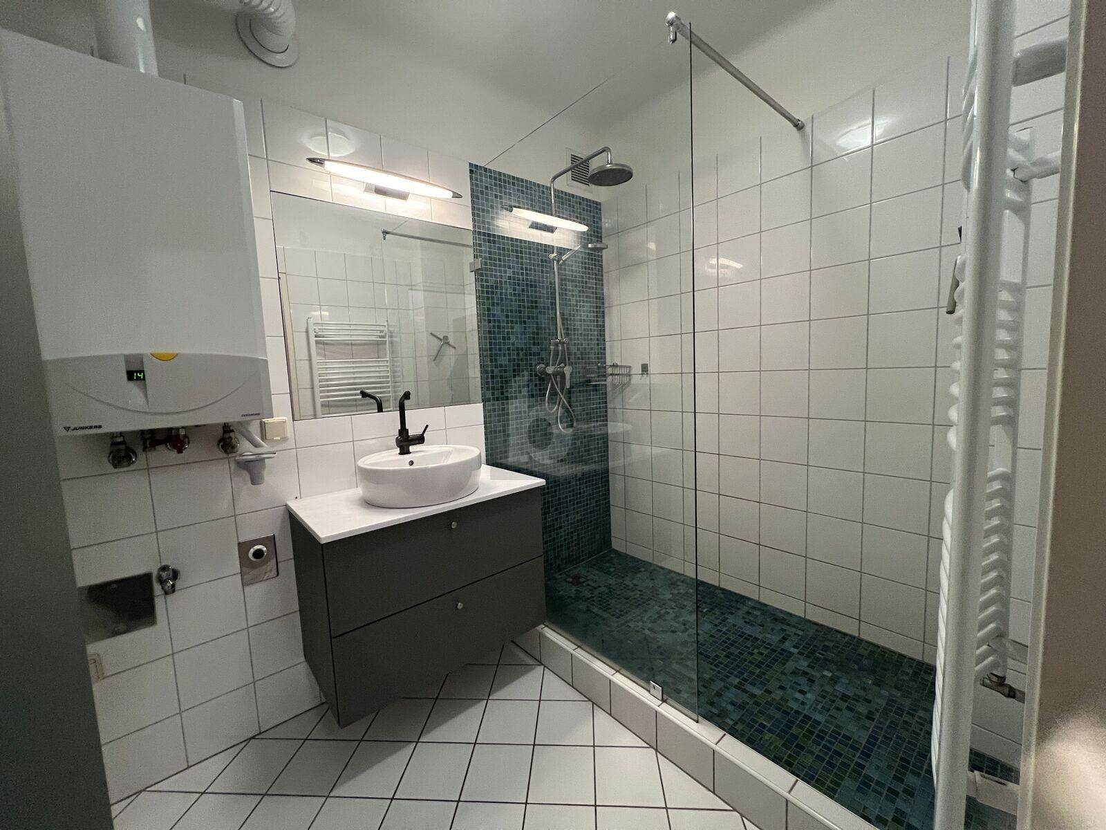 Modernes Badezimmer mit weiß gefliesten Wänden, Glasdusche und Regenbrause.