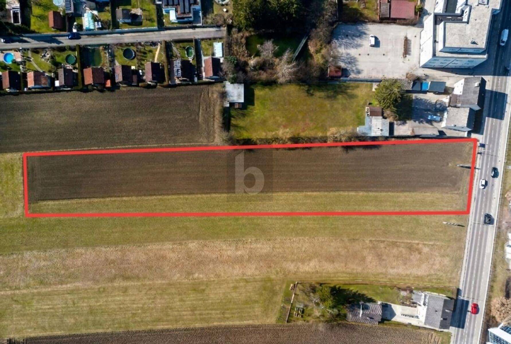 Luftaufnahme eines Feldes mit roter Umrandung, die ein spezifisches Grundstück hervorhebt.