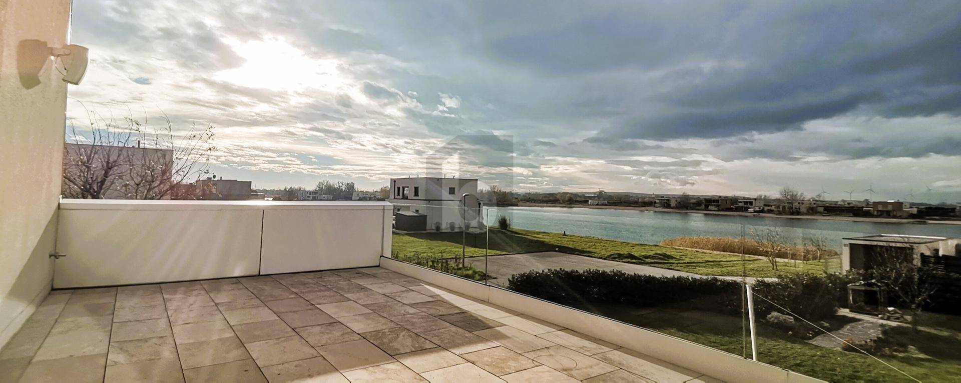 Geräumige Dachterrasse mit Fliesenboden und weitem Blick auf den See und die Umgebung.