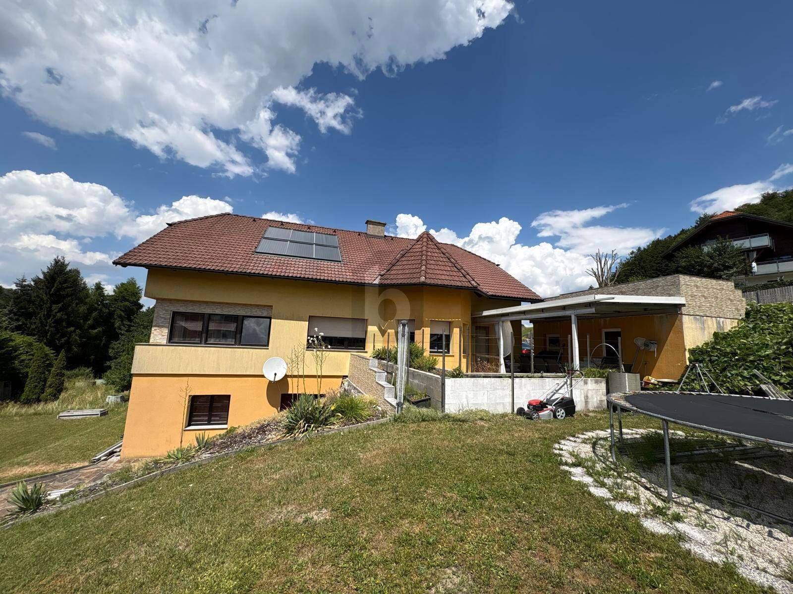 Rückseite des Hauses mit großem Garten, Photovoltaikanlage und Carport.
