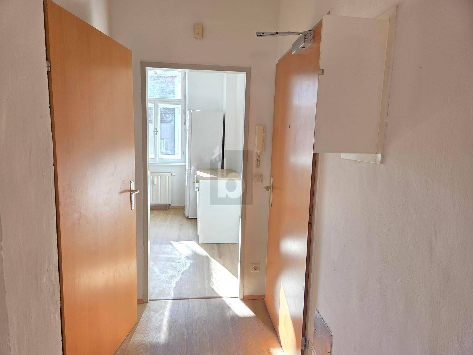 Heller Flur mit Zugang zur Küche, ausgestattet mit Laminatboden.